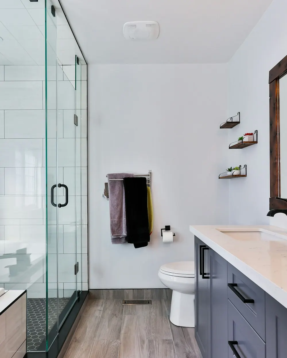 Remodeled bathroom with a frameless glass walk-in shower and a gray vanity