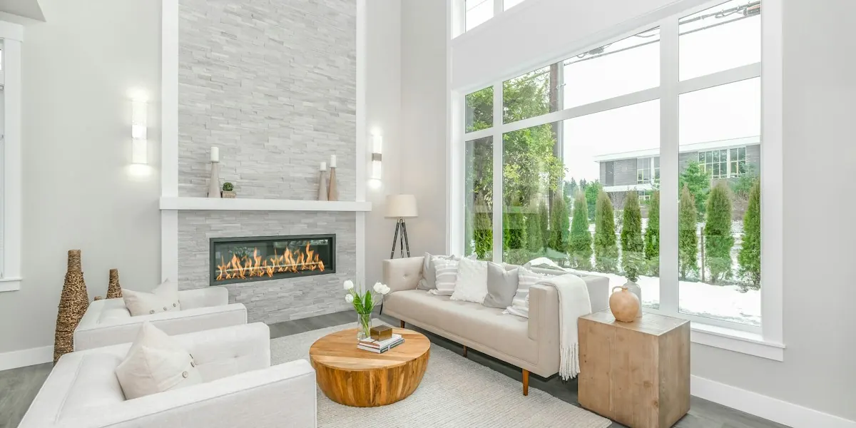 Bright renovated living room with double-height windows, a fireplace and white sofas