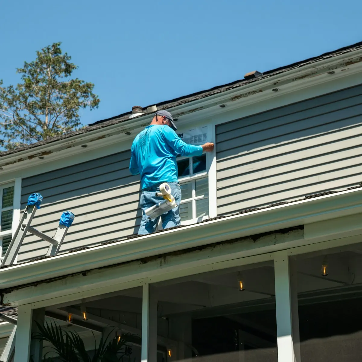 Painter working on the exterior siding of a two-story house