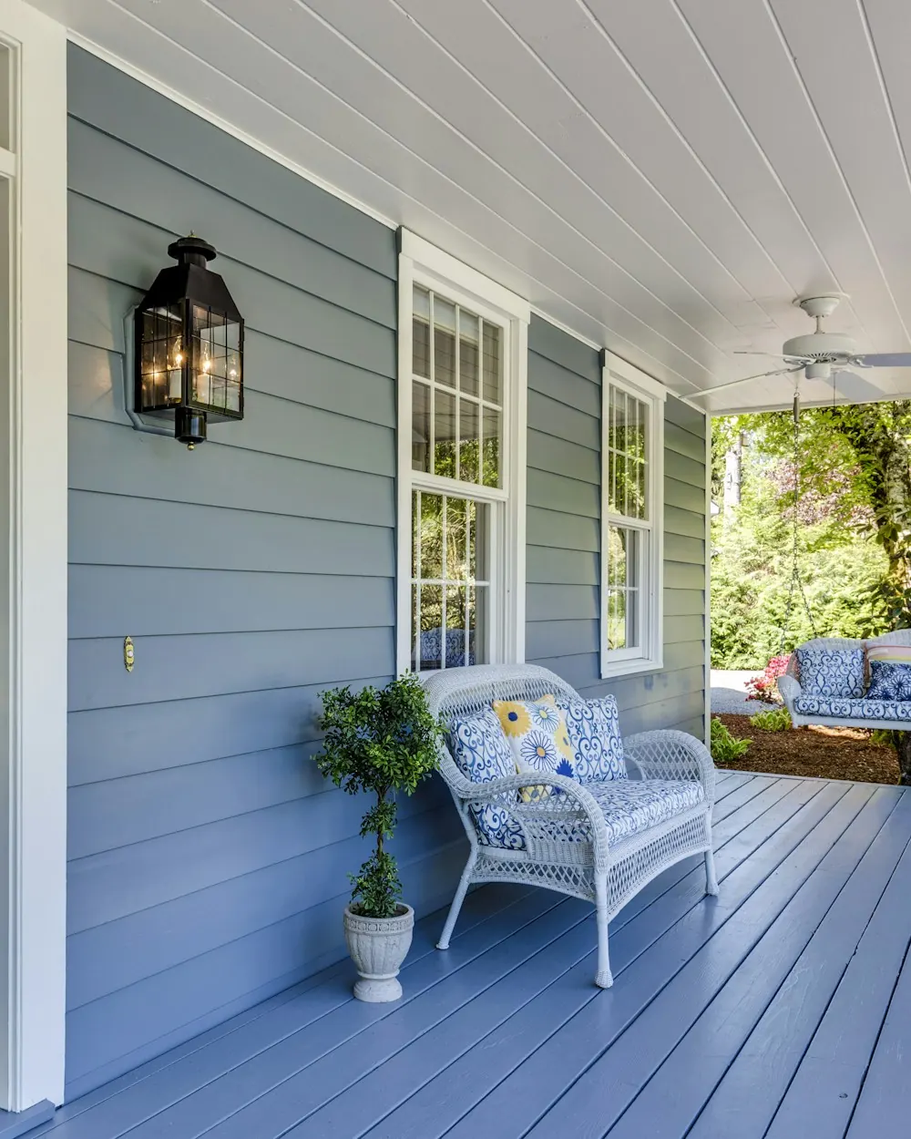 Front porch with freshly painted blue-gray siding and a navy front door