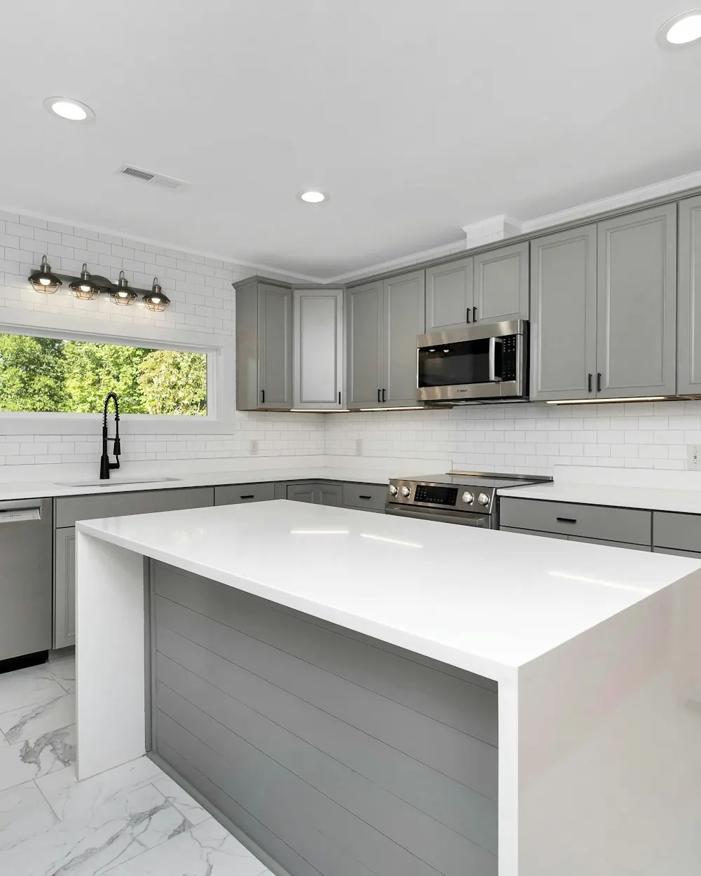 Kitchen with gray shaker cabinets and a white waterfall island