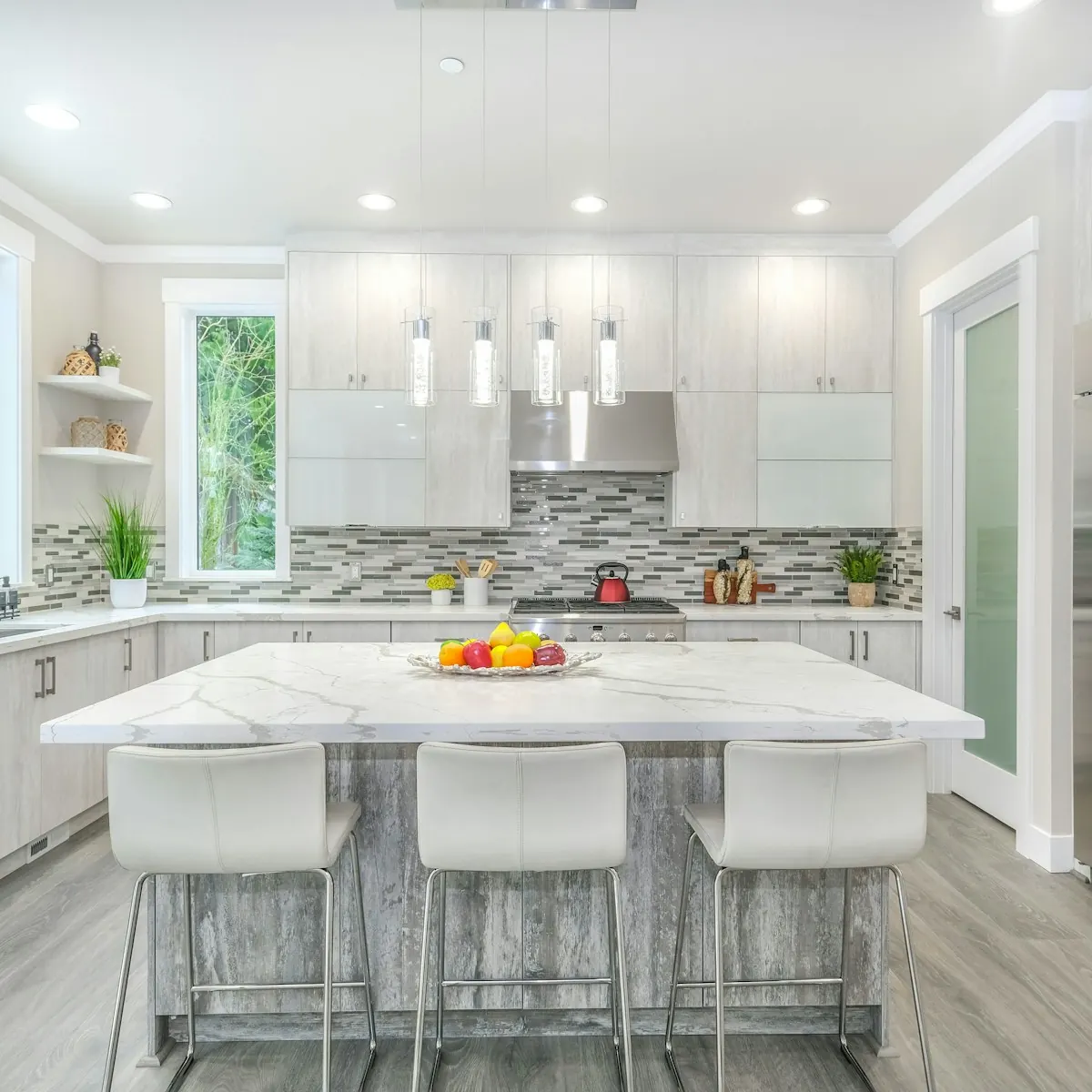Renovated kitchen with a marble-top island, white cabinets and stainless steel appliances
