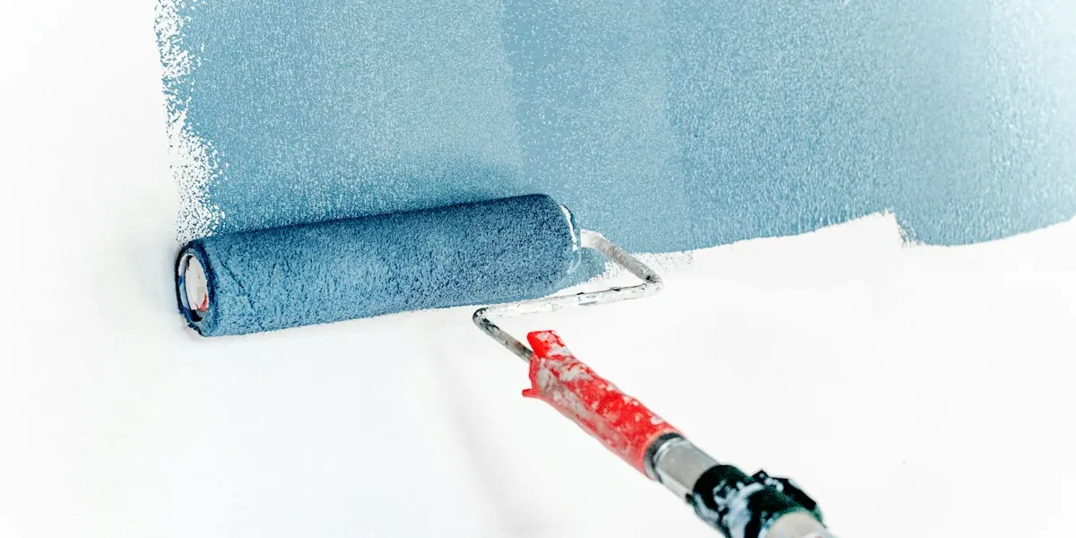 Paint roller applying a fresh coat of blue paint to a wall