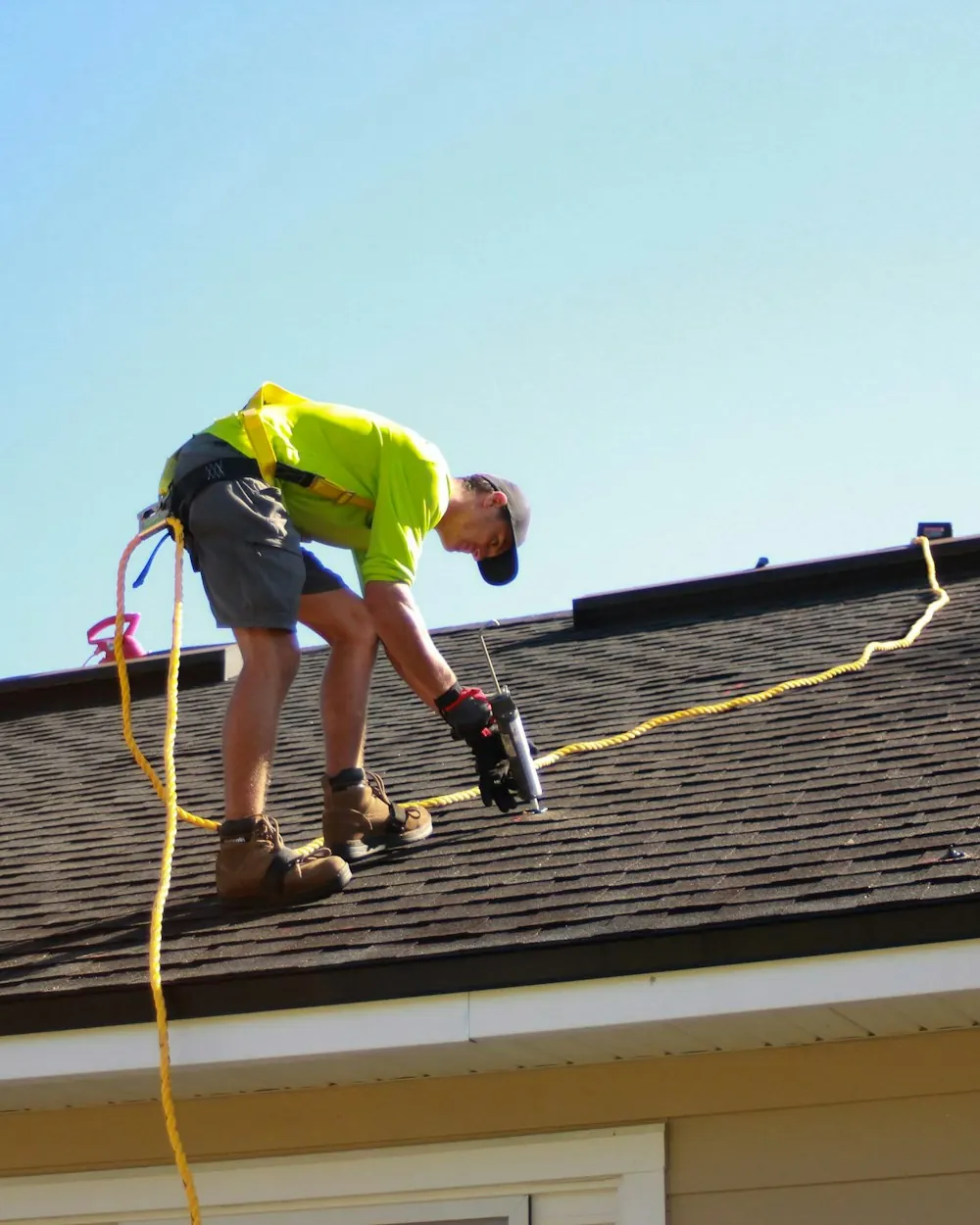 Roofer using a nail gun during a shingle roof replacement