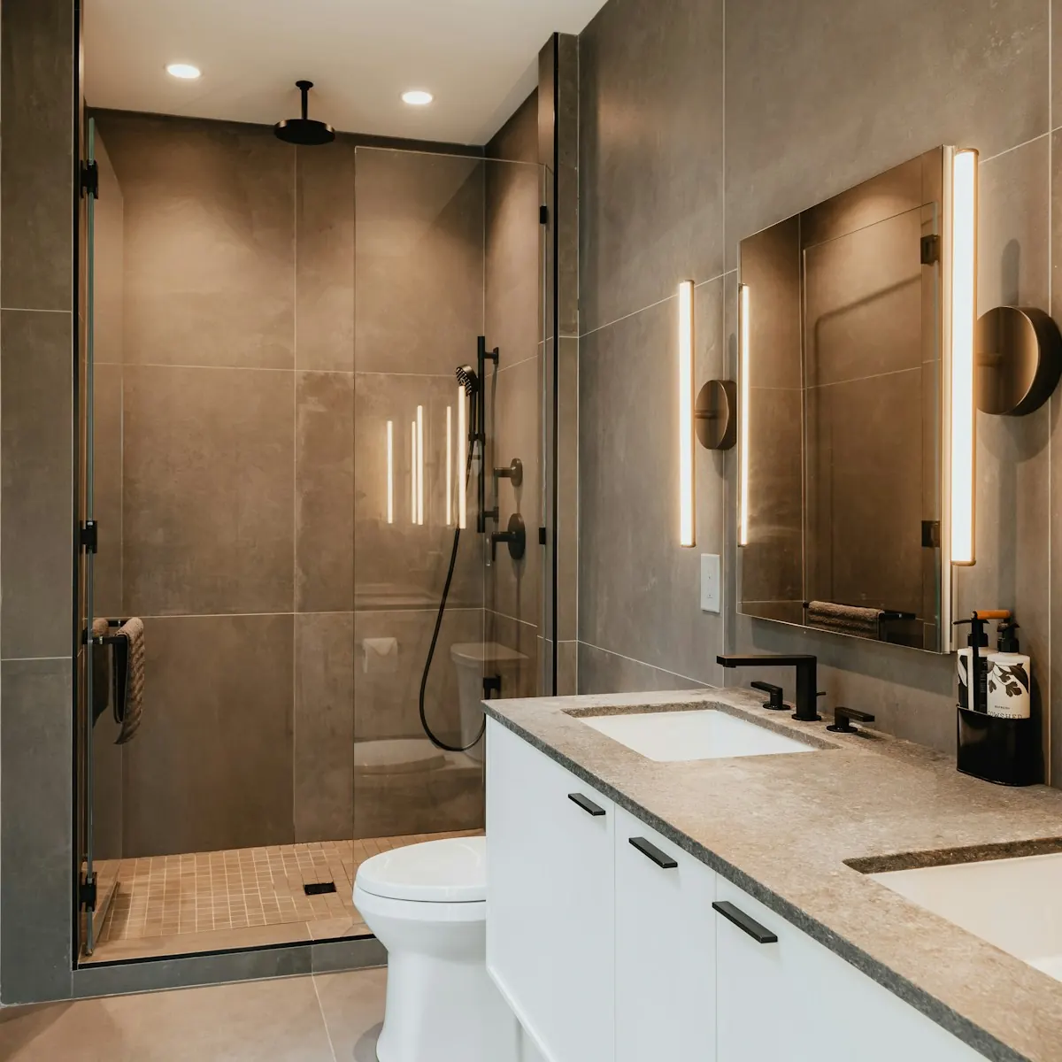 Walk-in glass shower with large-format tile next to a stone-top vanity