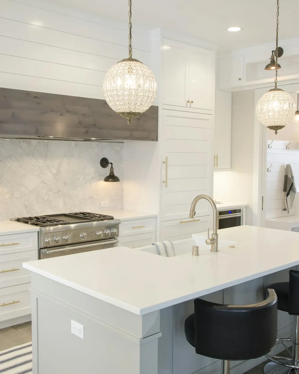 Remodeled white kitchen with a quartz island, pendant lights and black bar stools